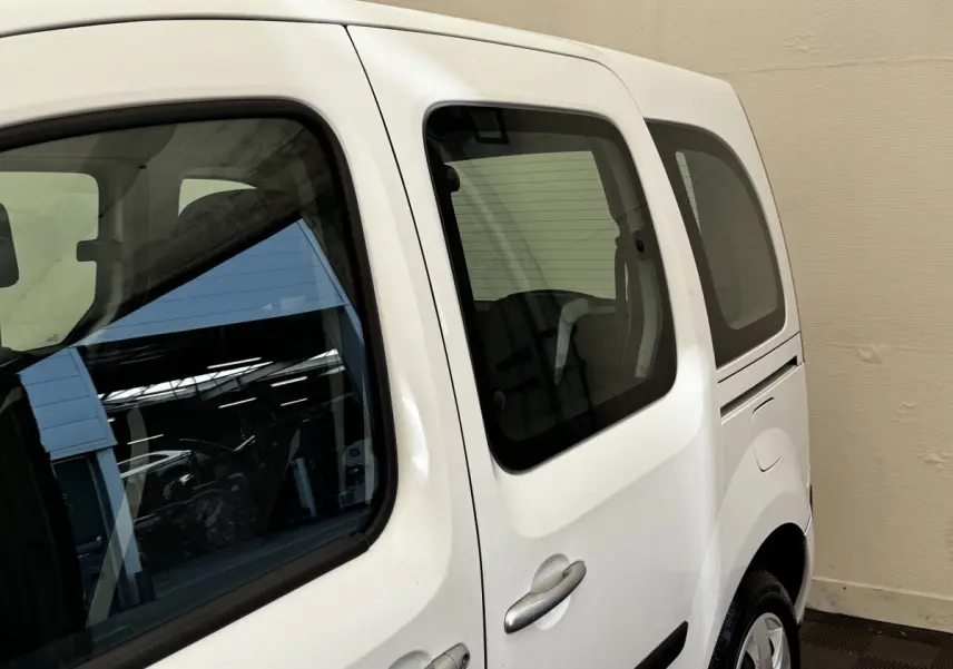 Vue latérale droite du Renault Kangoo blanc 2016, mettant en valeur les vitres teintées et la porte coulissante arrière.