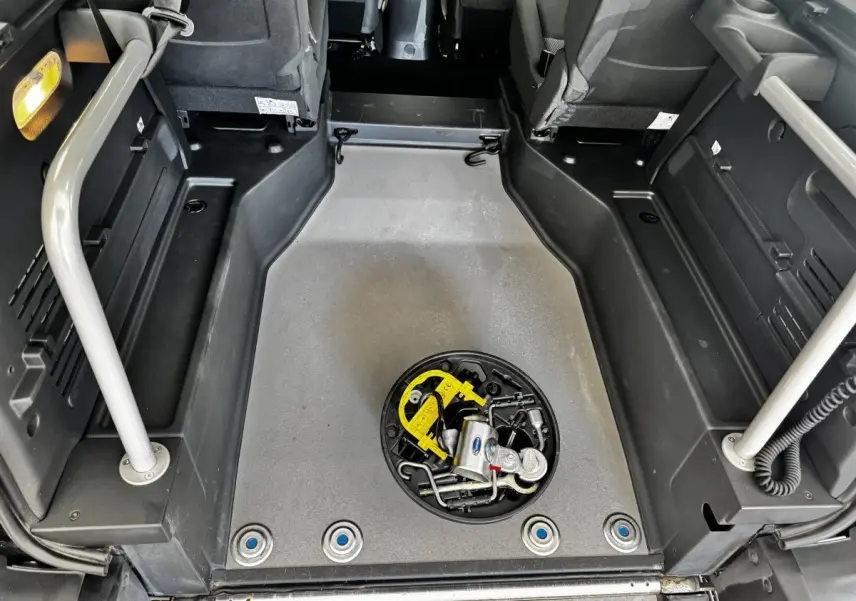 Vue intérieure du coffre du Renault Kangoo Zen blanc 2016, montrant le plancher plat avec outils rangés au centre.