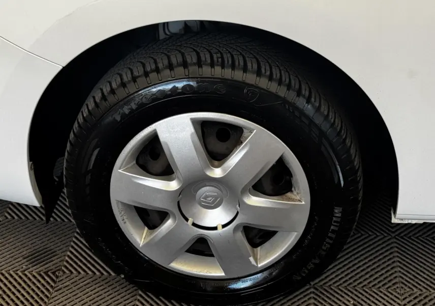 Gros plan sur la roue arrière droite d’un Renault Kangoo blanc, montrant le pneu Firestone et l’aile du véhicule.