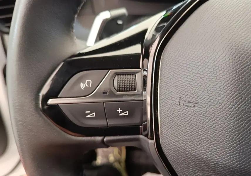 Gros plan sur le volant cuir noir de la Peugeot 2008 2021 avec commandes vocales et réglage du volume.