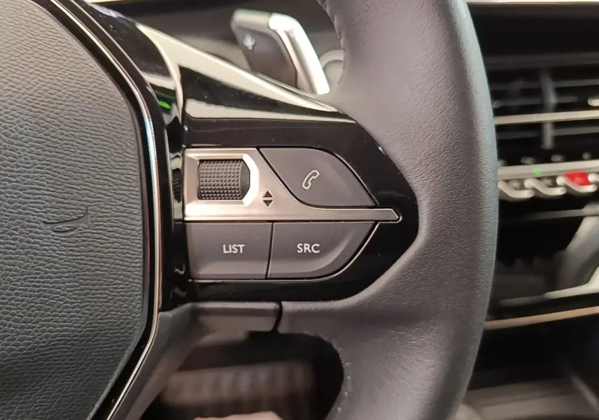Gros plan sur le volant cuir noir multifonctions du Peugeot 2008, avec commandes audio et téléphone intégrées.