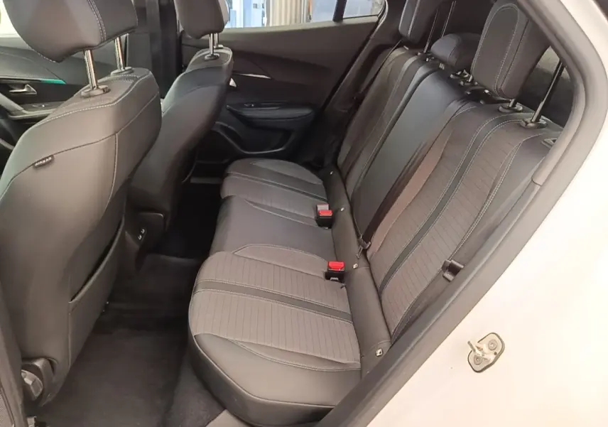 Vue intérieure côté droit sur la banquette arrière en tissu noir du Peugeot 2008 blanc, avec appuie-têtes et ceintures visibles.