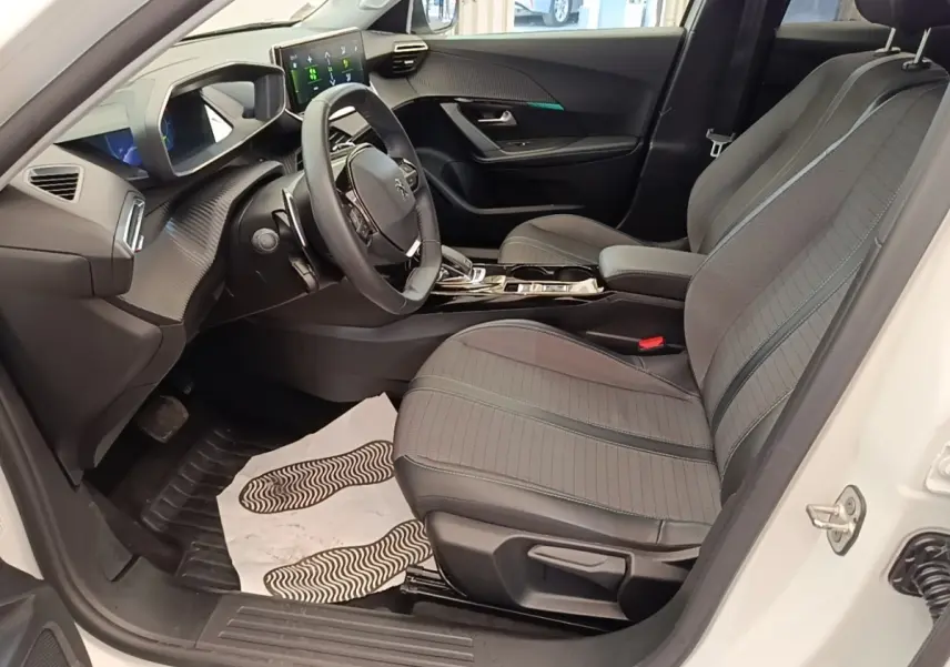 Vue intérieure côté conducteur du Peugeot 2008 blanc, avec sièges gris, volant cuir multifonctions et écran tactile.