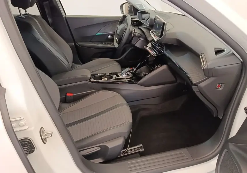 Vue intérieure côté conducteur du Peugeot 2008 blanc 2021, sièges tissu gris et tableau de bord avec écran tactile.