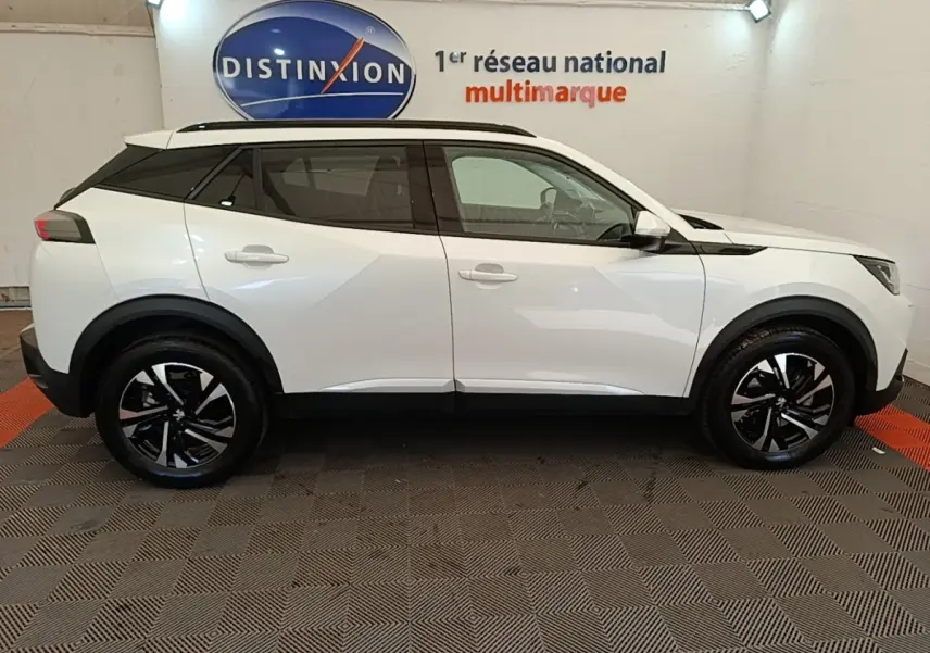 Peugeot 2008 blanc vue de profil côté gauche, avec jantes noires et toit noir contrastant en intérieur showroom.