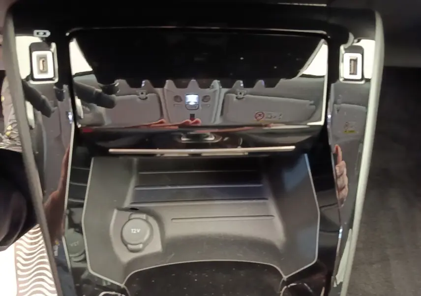 Gros plan sur la console centrale noire du Peugeot 2008 blanc, avec prise 12V visible et finition brillante.