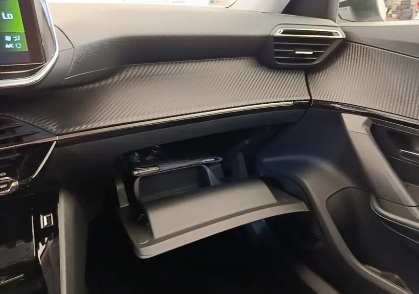 Vue intérieure côté passager du tableau de bord noir et boîte à gants ouverte avec rangement dans une Peugeot 2008 blanche.