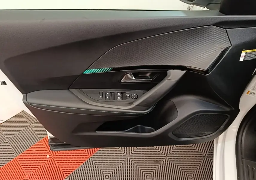 Vue intérieure côté gauche de la porte avant d'une Peugeot 2008 blanche avec garniture noire et commandes électriques.