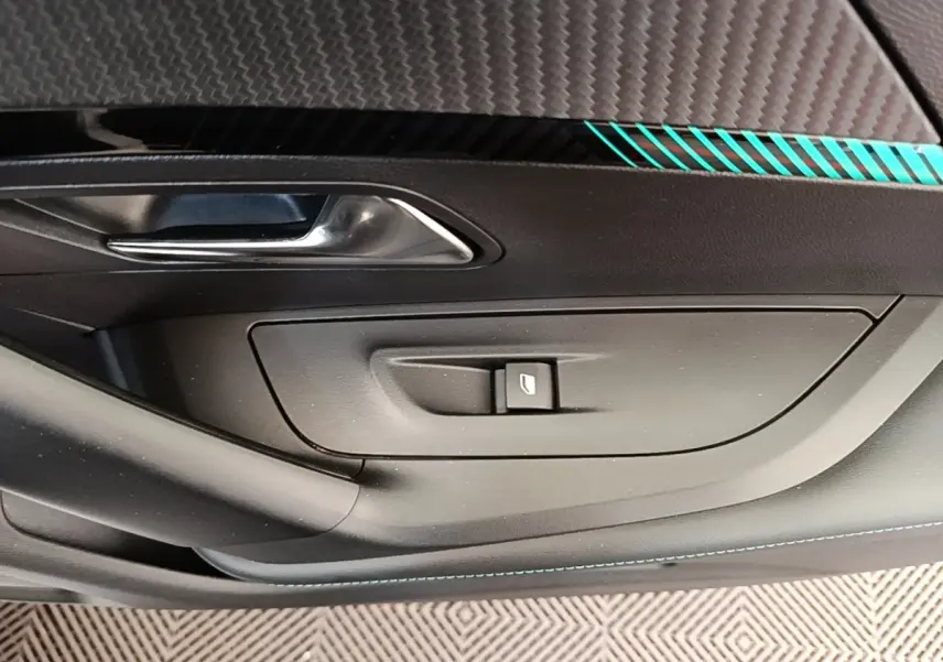 Détail de la porte intérieure côté conducteur du Peugeot 2008 blanc, avec poignée argentée et bouton de vitre électrique.