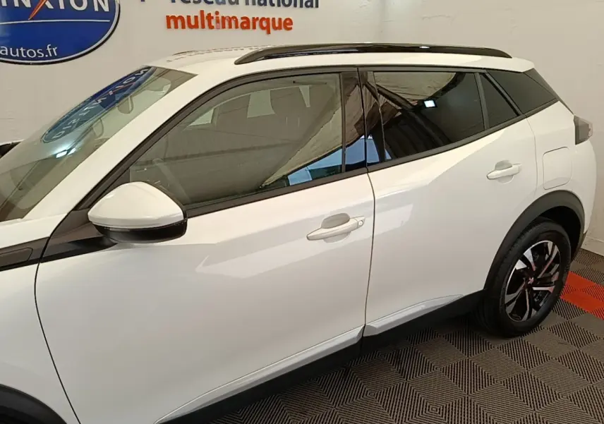 Vue latérale droite du Peugeot 2008 blanc de 2021 avec vitres teintées et jantes alliage noires et argentées.