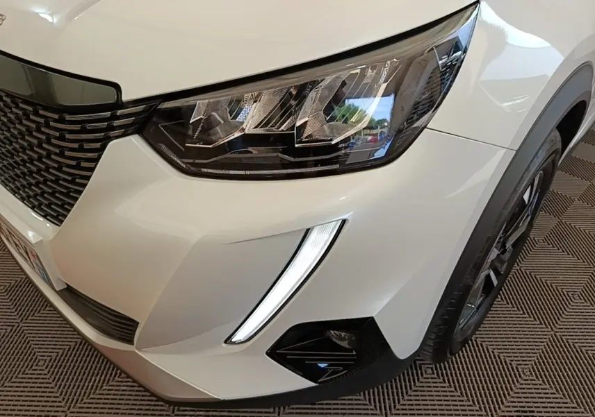 Gros plan sur l'avant droit blanc du Peugeot 2008 2021, mettant en valeur le phare LED et la calandre noire.