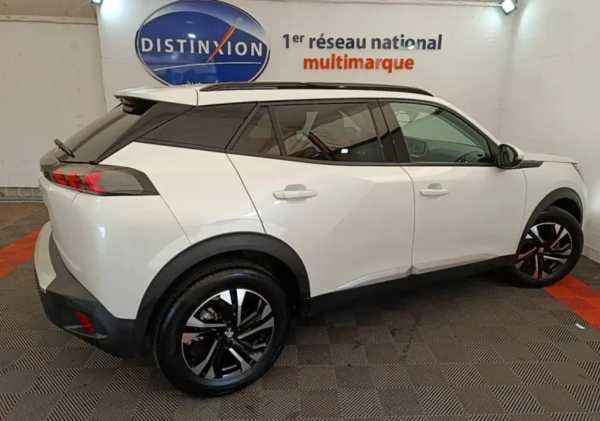 Peugeot 2008 blanc vue de profil droit en intérieur, avec toit noir et jantes alliage bicolores.