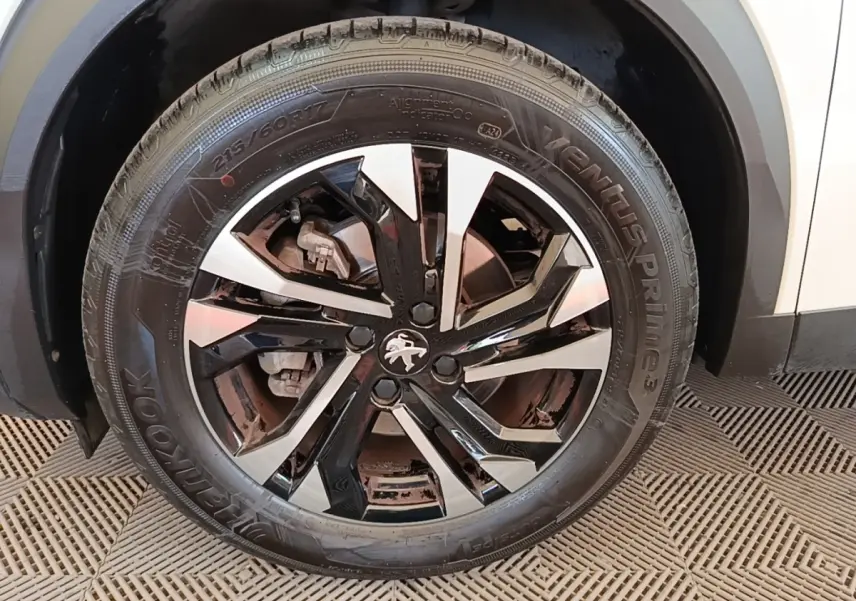 Gros plan sur la roue avant gauche blanche d’un Peugeot 2008 avec jante alliage noire et argentée.