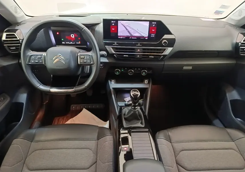 Vue intérieure avant de la Citroën C4 2021, tableau de bord noir avec écran tactile 10 pouces et volant cuir multifonctions.
