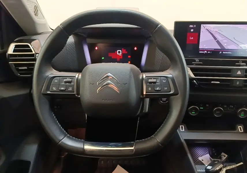 Vue intérieure centrée sur le volant cuir multifonctions de la Citroën C4 avec écran tactile de navigation visible.