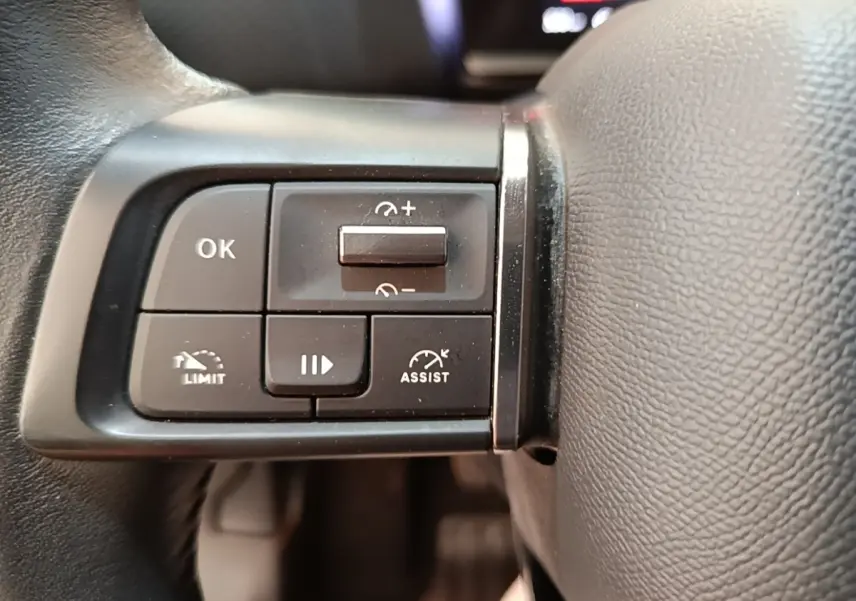 Gros plan sur les commandes noires multifonctions du volant cuir de la Citroën C4 gris clair, côté gauche.
