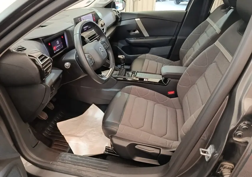 Vue intérieure côté conducteur de la Citroën C4 gris clair 2021, avec sièges tissu et cuir et tableau de bord digital.