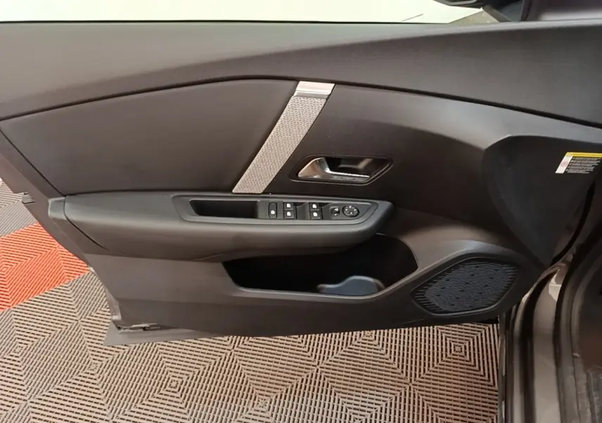 Vue intérieure du panneau de porte avant gauche gris foncé de la Citroën C4 avec commandes de vitres et haut-parleur intégré.
