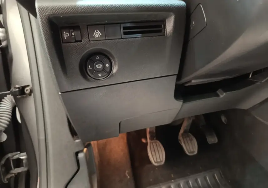Vue intérieure côté conducteur de la Citroën C4 2021, montrant les pédales et commandes de réglage des phares.