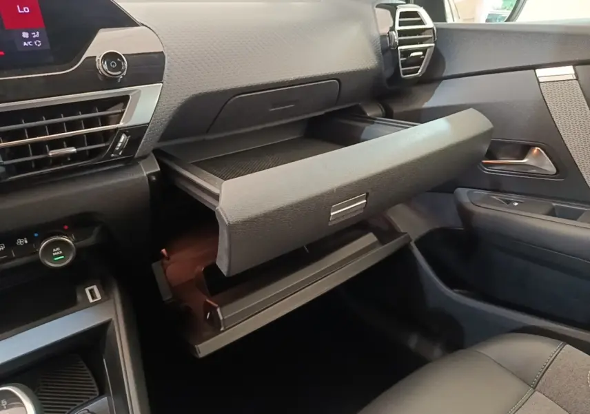 Vue intérieure côté passager de la Citroën C4 2021 gris clair, avec boîte à gants ouverte et tableau de bord moderne.