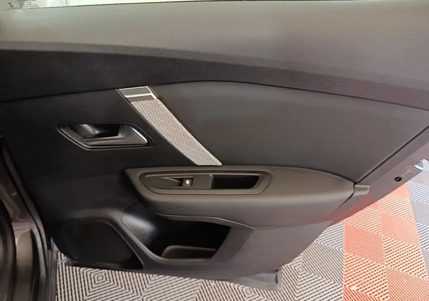 Vue intérieure côté gauche de la porte arrière d’une Citroën C4 gris clair avec poignée et commande de lève-vitre.