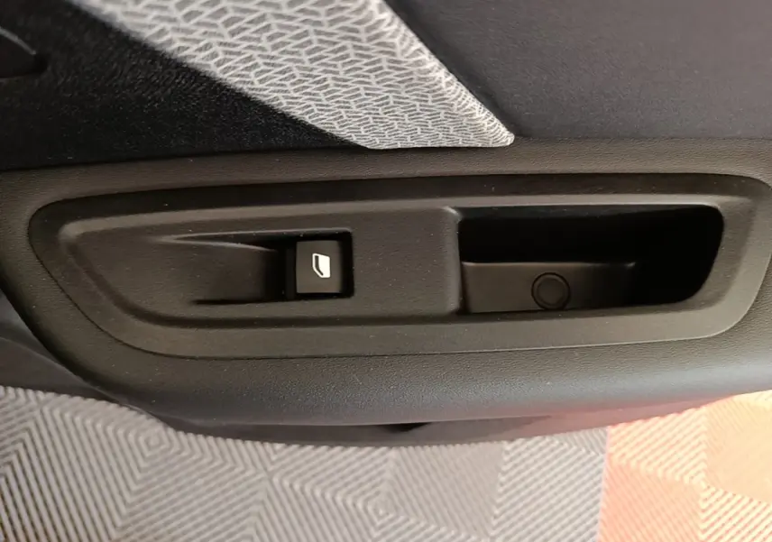 Gros plan sur la commande de lève-vitre électrique côté porte arrière d’une Citroën C4 gris clair.