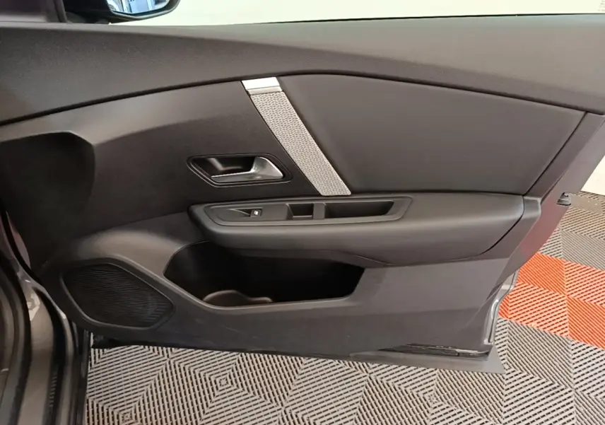 Vue intérieure côté gauche de la porte avant d'une Citroën C4 gris clair avec garniture noire et insert décoratif argenté.