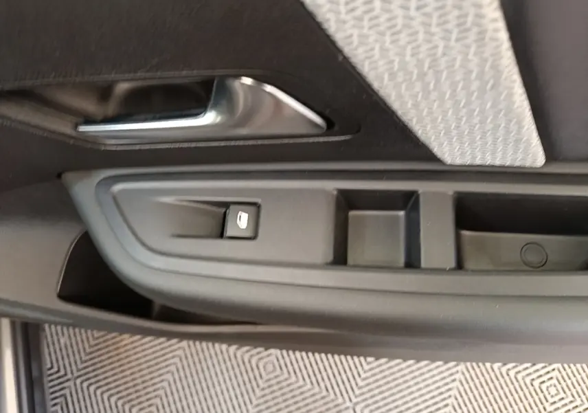 Détail de la porte côté conducteur d'une Citroën C4 gris clair, avec commande de lève-vitre et poignée intérieure.