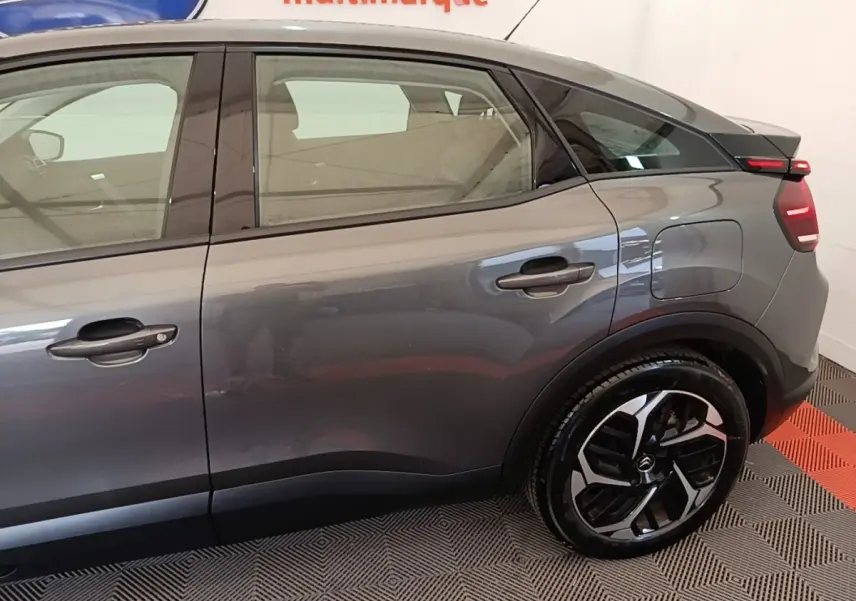 Vue latérale droite d'une Citroën C4 gris clair, mettant en valeur la porte arrière et la jante au design moderne.