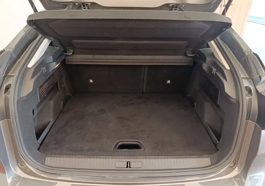 Coffre ouvert vu de l'arrière d'une Citroën C4 gris clair, montrant un espace de chargement propre et spacieux.