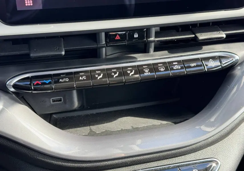Gros plan sur la console centrale de la Fiat 500 e 118ch MY24 Ice White pastel, montrant les commandes de climatisation et un port USB.