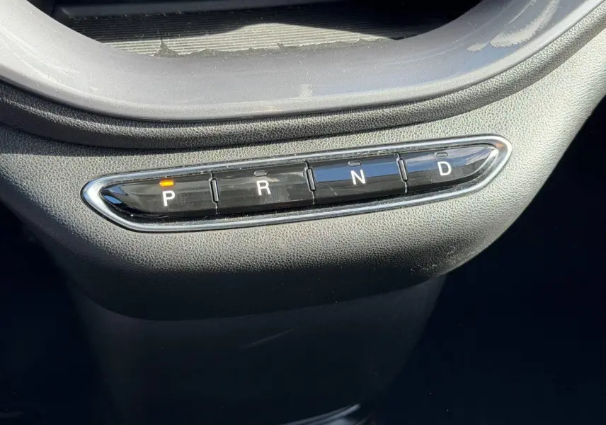 Gros plan sur la commande de boîte automatique avec boutons P, R, N, D dans une Fiat 500 e Ice White pastel 2024.