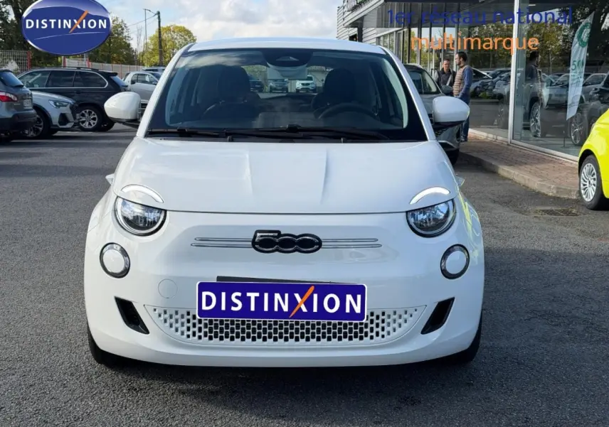 Vue avant d'une FIAT 500 électrique 2024 en Ice White pastel, avec logo distinctif et calandre ajourée basse.