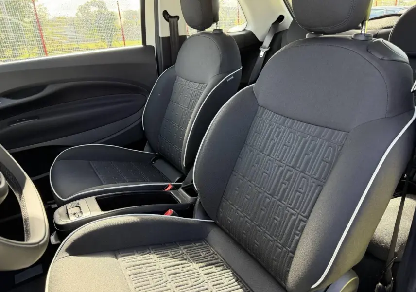 Vue intérieure des sièges avant noirs avec motif monogramme Fiat et surpiqûres blanches dans une Fiat 500 e 118ch MY24.
