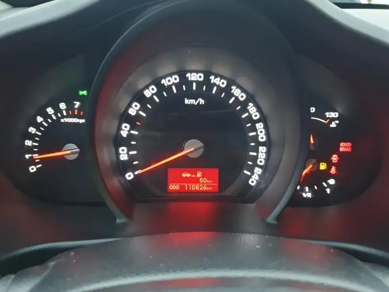 Vue rapprochée du tableau de bord du Kia Sportage blanc 2013, affichant le compteur de vitesse et les voyants allumés.