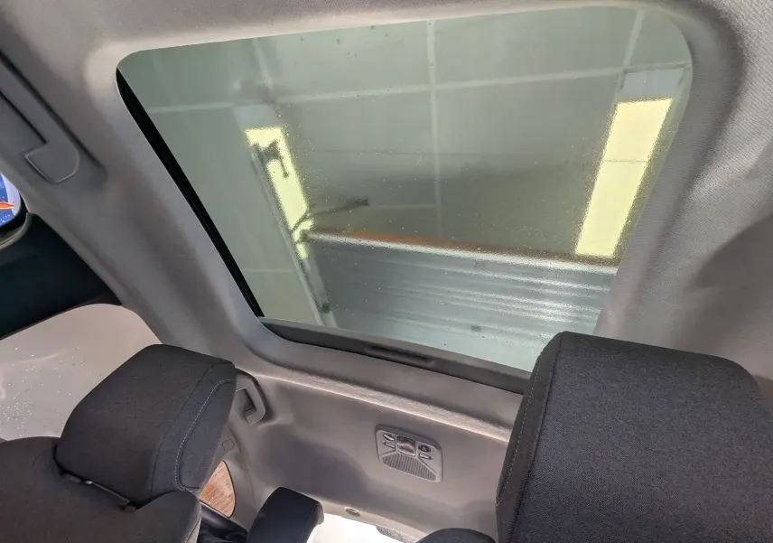 Vue intérieure du toit panoramique du Citroën C4 gris platinium 2024, avec appuie-têtes noirs et lumière ambiante.