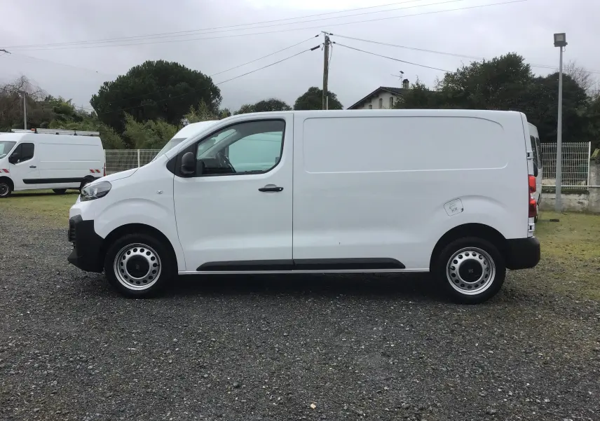 Vue de profil côté gauche d’un FIAT Scudo Fourgon blanc 2024 avec garde au sol réhaussée et jantes acier.