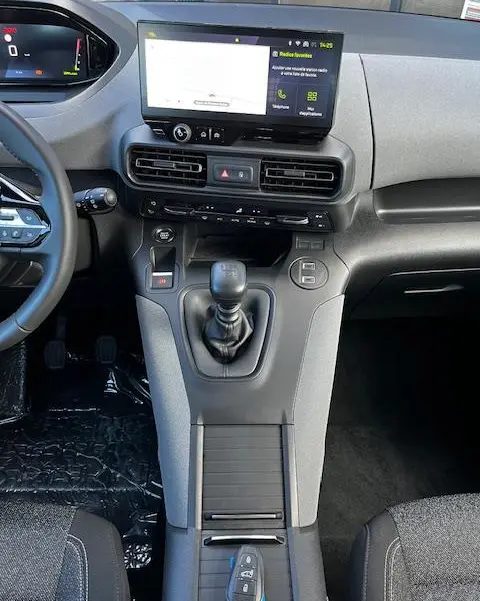 Vue intérieure centrée sur la console centrale du Peugeot Rifter 2024, avec écran tactile, boîte manuelle et clé posée.