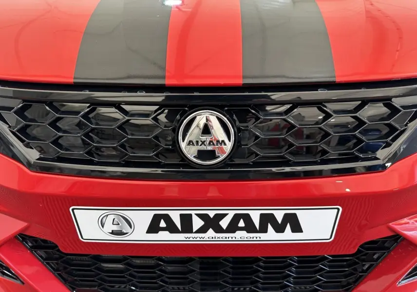 Gros plan avant sur la calandre noire et le logo AIXAM d'une AMBITION rouge avec bandes noires sur le capot.