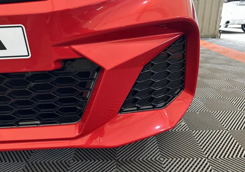 Gros plan sur la calandre avant droite rouge de l'AIXAM AMBITION 0.5 CITY COUPE GTI avec grille noire en nid d'abeille.