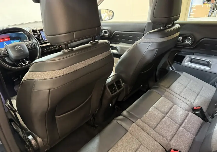 Vue intérieure arrière du Citroën C5 Aircross Hybrid avec sièges bi-matière gris et noir et tableau de bord visible à l'avant.