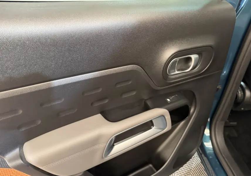 Gros plan sur la porte intérieure côté conducteur du Citroën C5 Aircross Hybrid bleu, avec accoudoir beige et poignée argentée.
