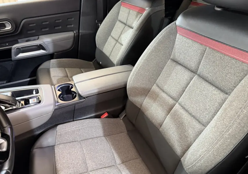 Vue rapprochée des sièges avant gris et noir avec bande rouge, intérieur du Citroën C5 Aircross Hybrid 225 ë-EAT8 Business.
