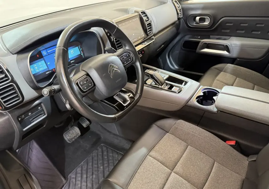 Vue intérieure côté conducteur du Citroën C5 Aircross Hybrid 225 avec tableau de bord numérique et sellerie grise.