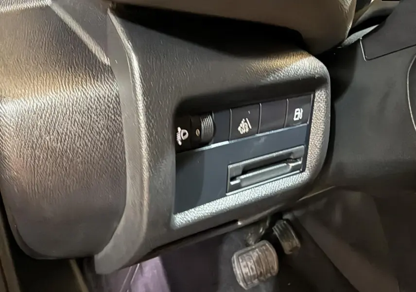Gros plan sur les commandes latérales noires du tableau de bord du Citroën C5 Aircross bleu, avec pédales visibles en dessous.