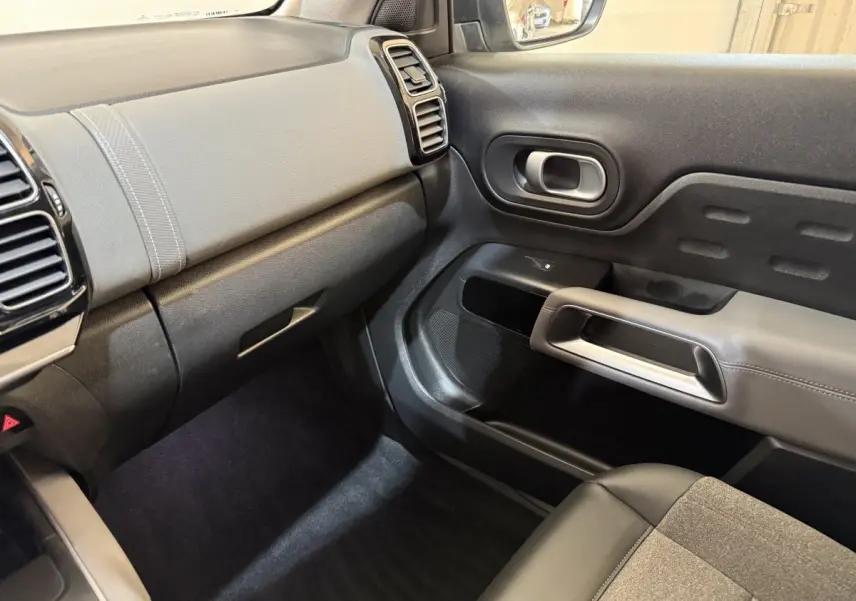 Vue intérieure côté passager du tableau de bord et de la porte du Citroën C5 Aircross Hybrid bleu, avec garnitures grises et noires.