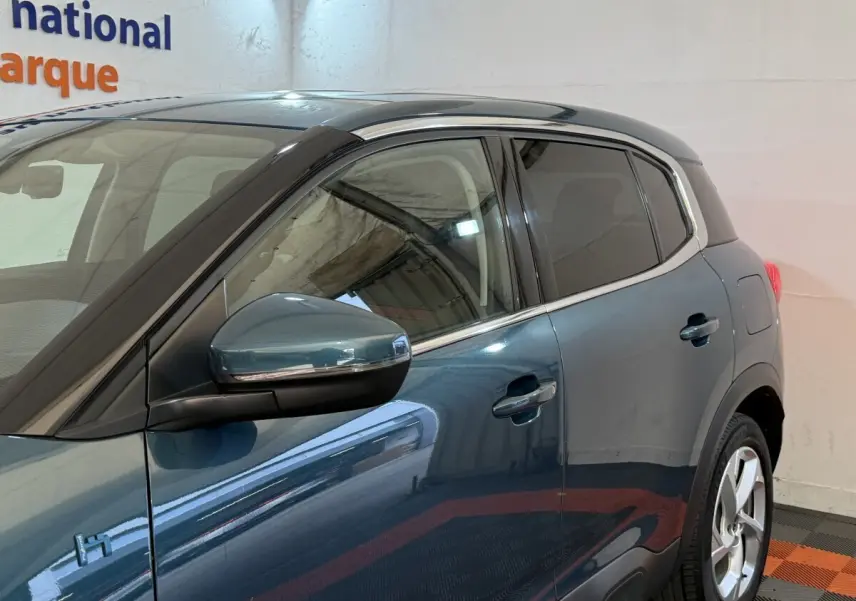Vue côté gauche arrière du Citroën C5 Aircross Hybrid bleu avec rétroviseur rabattable électriquement et vitres teintées.