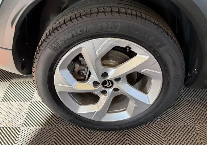Gros plan sur la roue avant droite avec jante argentée et pneu Michelin du Citroën C5 Aircross bleu hybride.