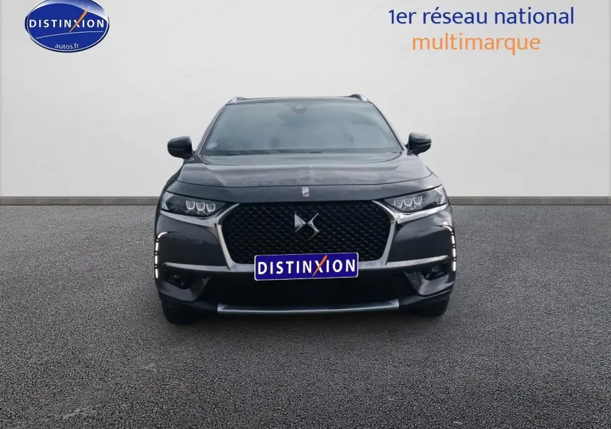 Vue frontale d'un DS7 Crossback E-tense gris platinium avec calandre noire et feux LED distinctifs allumés.