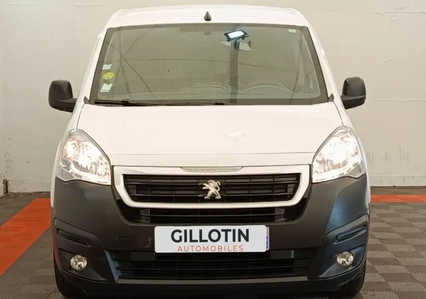 Vue frontale d'un Peugeot Partner blanc 2018 avec pare-chocs noir et phares allumés en intérieur.